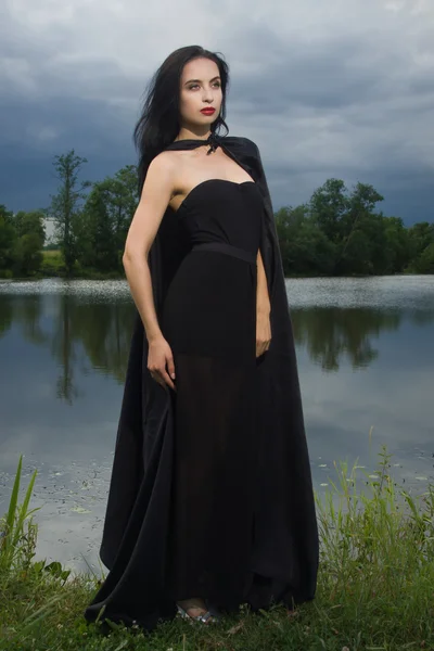 Mooie brunette vrouw in zwarte jurk en zwarte mantel — Stockfoto