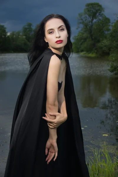 Bella donna bruna in abito nero e mantello nero — Foto Stock