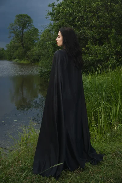 Mooie brunette vrouw in zwarte jurk en zwarte mantel — Stockfoto