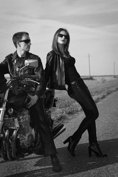 Motociclista hombre y chica se para en el camino —  Fotos de Stock
