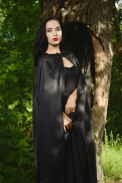 Mooie brunette vrouw in zwarte jurk en zwarte mantel — Stockfoto