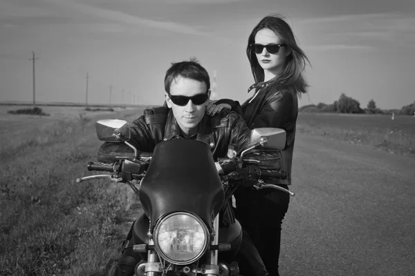 Motociclista hombre y chica se para en el camino —  Fotos de Stock