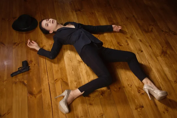 Woman in a black suit with gun lying on the floor — Stock Photo, Image