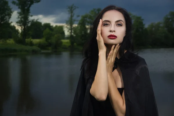 Mooie brunette vrouw in zwarte jurk en zwarte mantel — Stockfoto