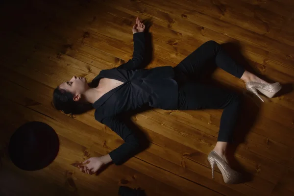 Kvinna i en svart kostym med pistol liggande på golvet — Stockfoto