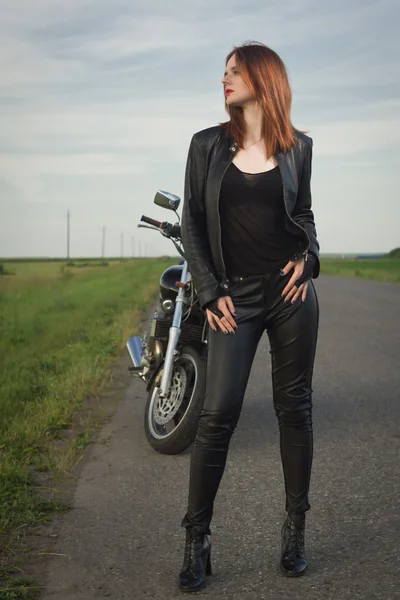 Chica motorista en una chaqueta de cuero posando cerca de la motocicleta —  Fotos de Stock