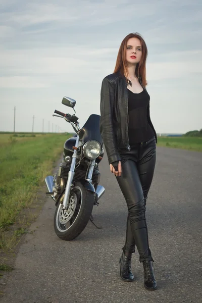 Chica motorista en una chaqueta de cuero posando cerca de la motocicleta —  Fotos de Stock