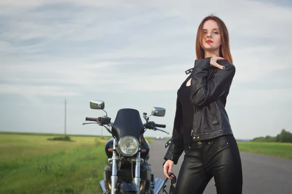 Biker meisje in een lederen jas poseren in de buurt van motorfiets — Stockfoto