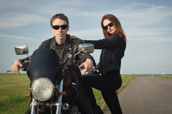 Motociclista hombre y chica se para en el camino —  Fotos de Stock