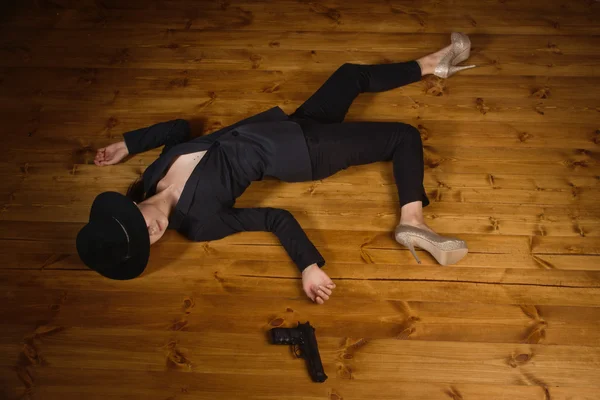 Mujer en traje negro con pistola tirada en el suelo —  Fotos de Stock