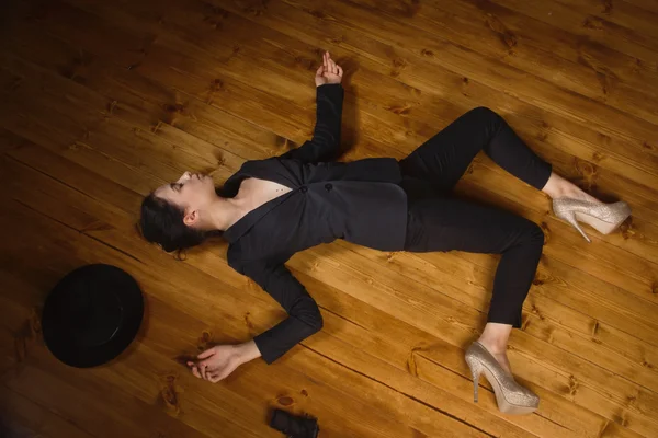 Woman in a black suit with gun lying on the floor — Stock Photo, Image