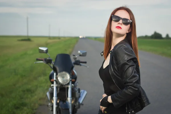 Menina motociclista em uma jaqueta de couro posando perto de moto — Fotografia de Stock