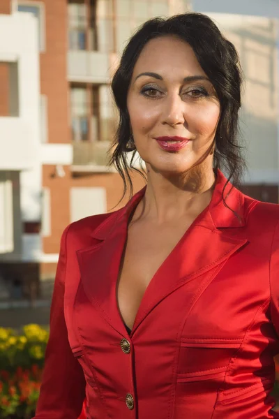 Attractive business woman in red suit on a street — Stock Photo, Image