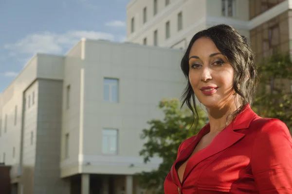 Attractive business woman in red suit on a street — Stock Photo, Image