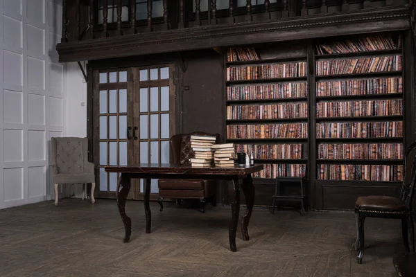 革のアームチェア 木製のテーブルと本棚付きの古典的な図書室 — ストック写真