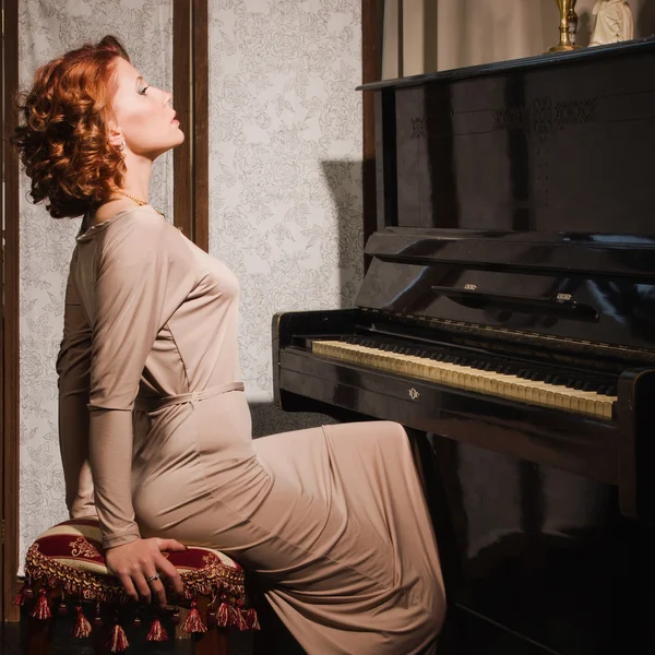 Mulher de beleza em vestido de noite tocando piano — Fotografia de Stock