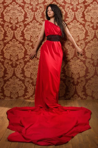Modieuze brunette in een lange rode jurk — Stockfoto
