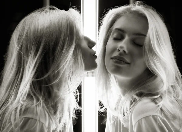 一个华丽的金发女郎，亲吻自己的镜像的镜头 — 图库照片