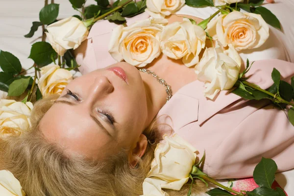 Hermosa mujer con rosas acostada en la cama — Foto de Stock