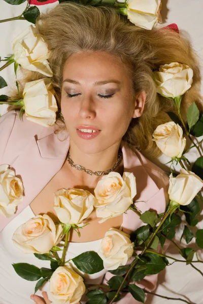 Vacker kvinna med rosor ligger på sängen — Stockfoto