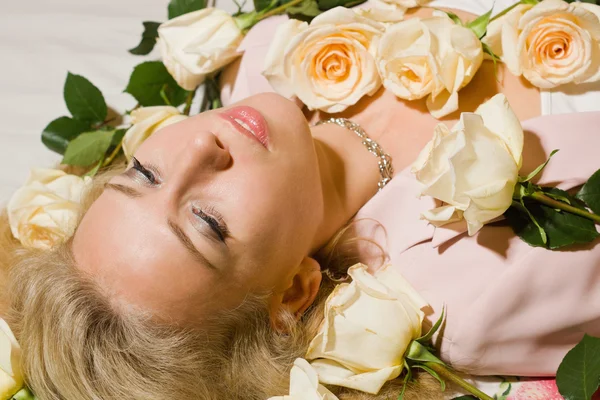 Hermosa mujer con rosas acostada en la cama — Foto de Stock