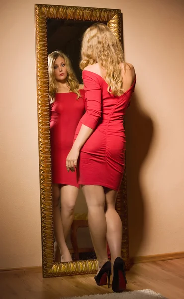 Fashionabla lady tittar på hennes reflektion i spegeln — Stockfoto