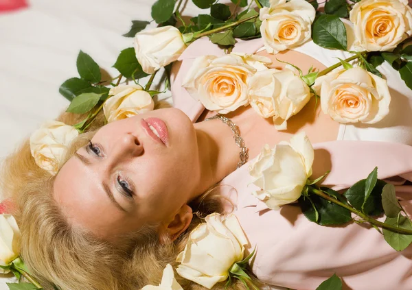 Mooie vrouw met rozen liggend op het bed — Stockfoto