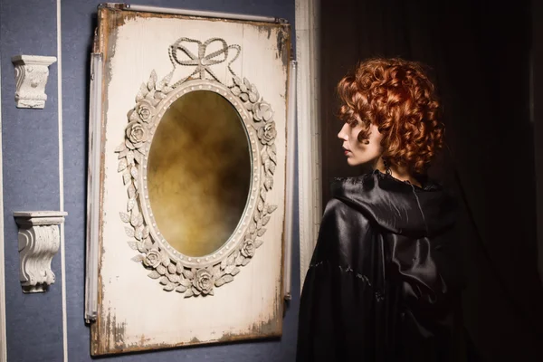 Очень красивая женщина-вампир смотрит на свое отражение в зеркале — стоковое фото