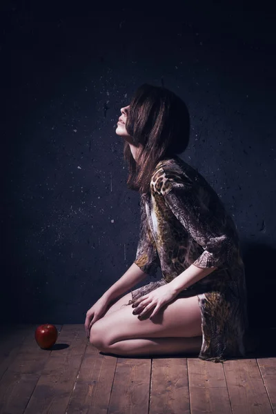 Lonely mad woman with red apple sitting on a floor — Stock Photo, Image