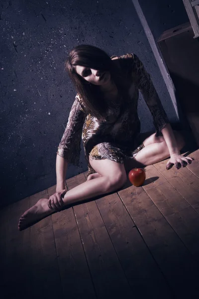 Lonely mad woman with red apple sitting on a floor — Stock Photo, Image