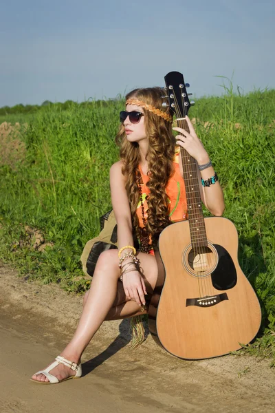 Joven chica hippie en un campo de verano con su guitarra — Foto de Stock