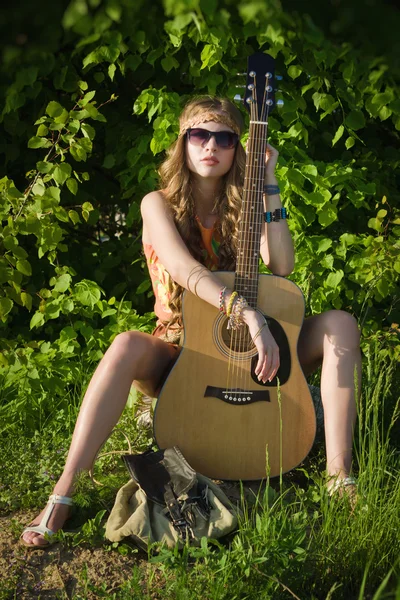 Hippie-Mädchen unterwegs mit ihrer Gitarre auf einer Straße — Stockfoto