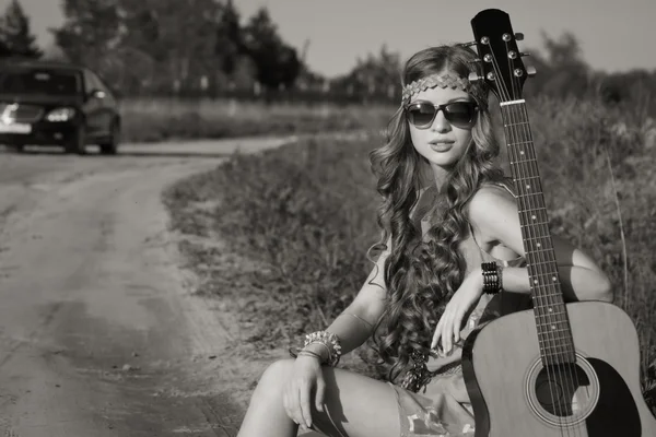 Hipis dziewczyna podróżujący z gitarą na drodze — Zdjęcie stockowe