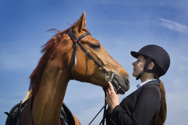 Beautiful young girl jockey talks with her horse — Stock Photo, Image