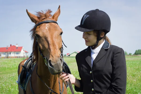 Красивая девушка-жокей разговаривает со своей лошадью — стоковое фото