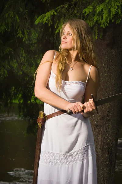 Menina bonita em vestido branco segurando uma espada medieval — Fotografia de Stock