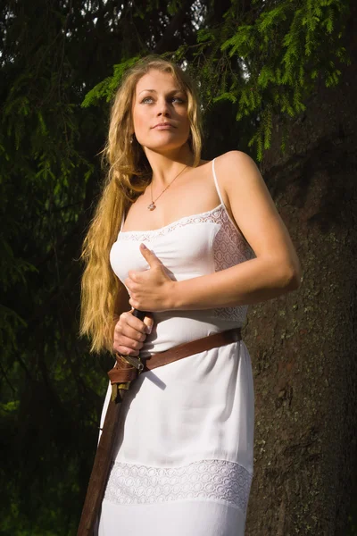 Beautiful young girl in white dress holding a medieval sword — Stock Photo, Image