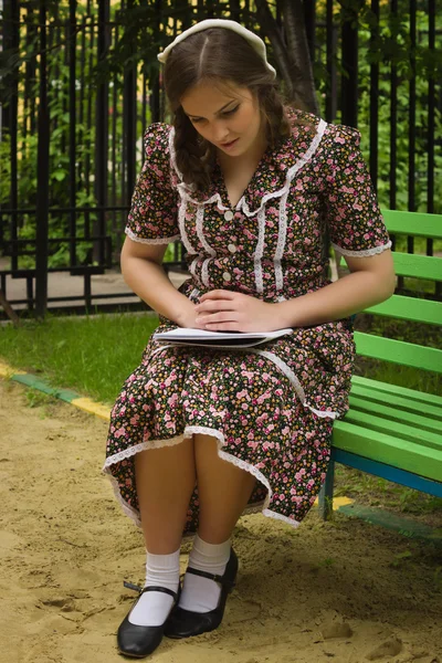 Sowjetmädchen im Retro-Stil mit einem Notenbuch auf einer Bank sitzend — Stockfoto