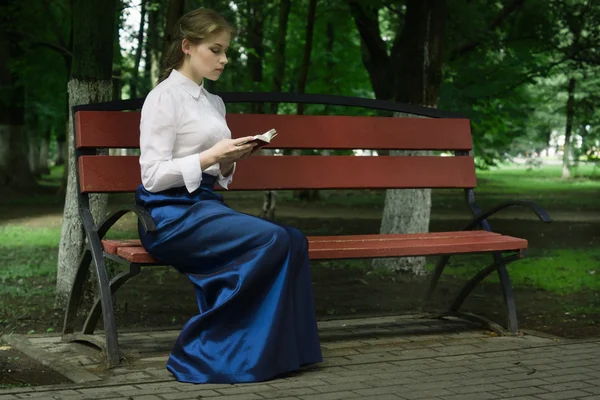 Donna russa in stile retrò con un libro seduto su una panca in t — Foto Stock