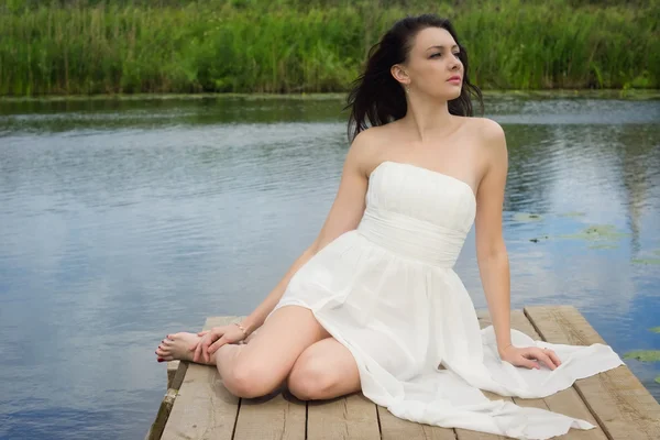 Ontspannen jonge vrouw op houten pier op het meer — Stockfoto