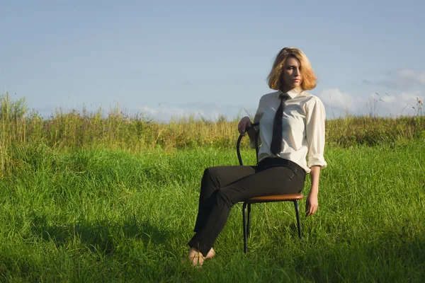 Красуня жінка сидить у кріслі на полі — стокове фото