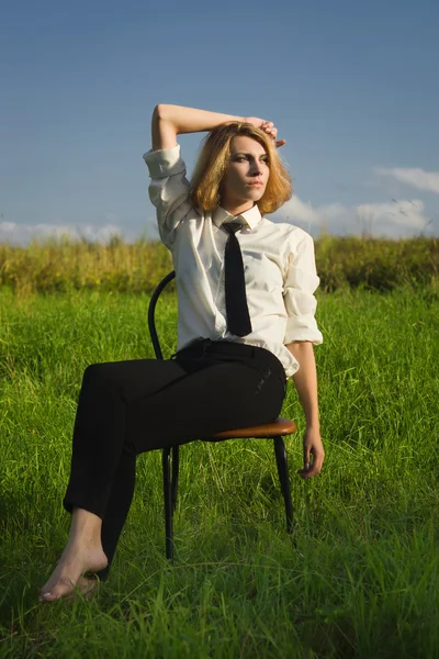 Beauty woman sitting in the armchair at the field — Stock Photo, Image
