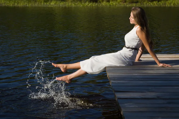Ontspannen jonge vrouw op houten pier op het meer — Stockfoto