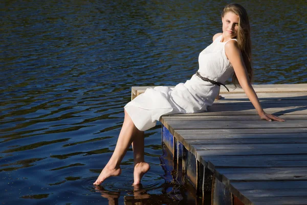 Relajante joven en el muelle de madera en el lago — Foto de Stock