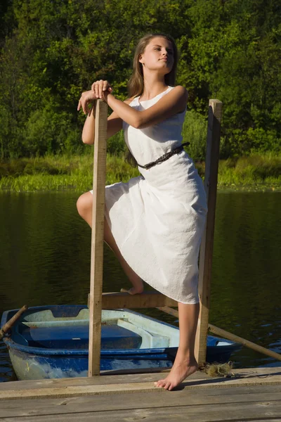 Rilassante giovane donna sul molo di legno al lago — Foto Stock