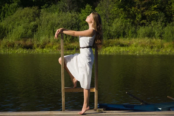 Relaksujący młoda kobieta na drewniane molo nad jeziorem — Zdjęcie stockowe