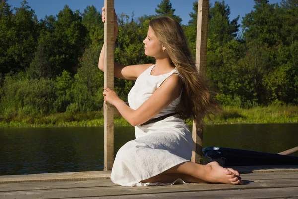 Розслаблююча молода жінка на дерев'яному пірсі біля озера — стокове фото