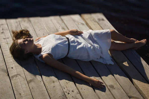Genç kadın gölde ahşap iskele üzerinde rahatlatıcı — Stok fotoğraf