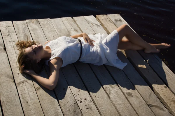 Rilassante giovane donna sul molo di legno al lago — Foto Stock