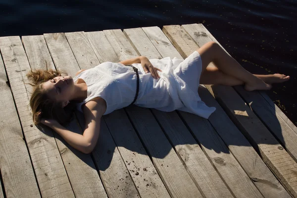 Ontspannen jonge vrouw op houten pier op het meer — Stockfoto